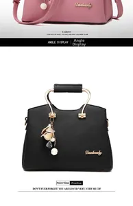 Detail of lychee textured PU leather handbag with metal ring handle and floral pendant