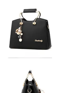 Detail view of black lychee leather handbag with golden ring handles and floral charms