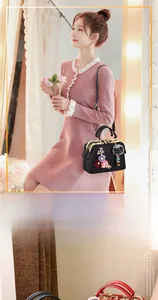 Detail of black Boston bag featuring pink floral appliques and a grey fur pompom charm