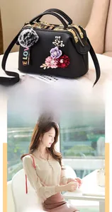 Detail of elegant black crossbody bag with 3D floral decorations and gray fur pompom