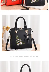 Dettaglio di elegante ricamo floreale su borsa a tracolla vintage nera con finiture d'oro