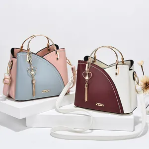 Schicke Handtasche im Color-Block-Design mit Metallgriffen und Herzanhänger auf Weiß