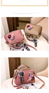Detail of floral box handbag with 3D purple flowers, gold hardware and pompom charm