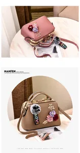 Close-up of faux leather handbag with 3D fabric flowers and plush pom-pom charm