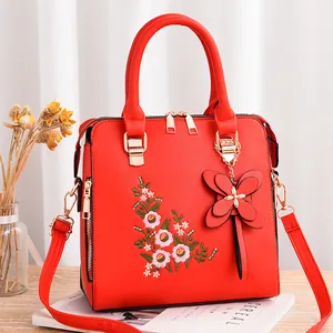 Borsa a mano rossa ricamata da donna con motivi floreali e un ciondolo a farfalla