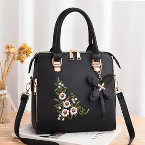 Elegante borsa nera con ricami floreali e accessorio pendente a forma di farfalla