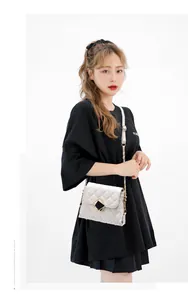 Close-up of white quilted chain bag with elegant black and gold square diamond lock