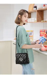 Detail of quilted leather crossbody bag with chain strap and metal lock closure