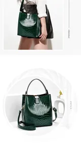 Macro view of dark green crocodile texture on glossy bucket bag with gold metal buckle