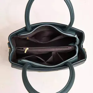 Detailed interior of dark teal multi-compartment handbag with central zipper pocket