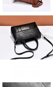 Détail du sac à main en similicuir noir montrant le mélange de textures crocodiles