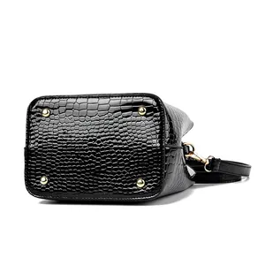 Glossy black crocodile pattern bucket bag showing bottom view with gold protective metal feet