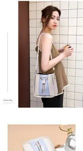 Stylish white and blue bucket bag with gold chain and star charm detail shown by a model