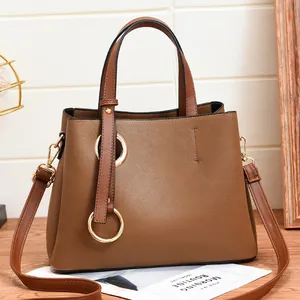 Brown PU leather tote bag with gold ring hardware and detachable shoulder strap on a table