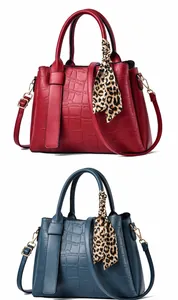 Dettaglio di borse rosso e blu scuro motivo coccodrillo con sciarpe leopardate eleganti