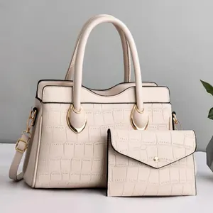 Detail of cream crocodile textured tote bag with matching wallet and golden hardware