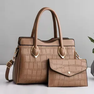 Detailed view of brown crocodile-patterned tote and envelope pouch with gold hardware