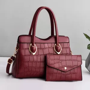 Detail view of burgundy crocodile-textured tote bag set with matching wallet and gold hardware