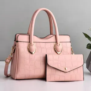 Detail of pink faux crocodile leather handbag set with gold hardware and small pouch