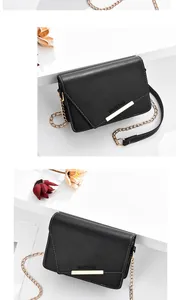 Detalle de bolso bandolera de cuero negro con cadena dorada y texto Romantic Paris