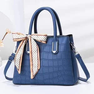 Detailed close-up of blue stone pattern leather bag with decorative silk scarf and silver hardware