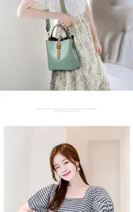 Detail view of mint green bucket bag with brown strap and golden buckle on model