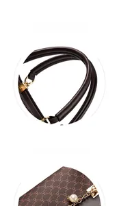 Detail of round top handles with gold hardware and a pearl leaf pendant on a brown tote