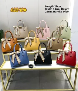 Nine colorful stone pattern handbags on display rack with silk scarf and shoulder strap detail