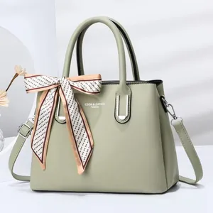 Detail of sage green faux leather tote bag with floral silk scarf and silver hardware