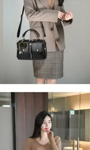 Détail du sac à main noir en simili cuir avec poches, pompon vert et bandoulière