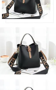Close-up of black bucket bag with a wide patterned strap and brown leather buckle