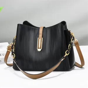 Chic black bucket bag with wave texture, brown leather straps and gold chain detail