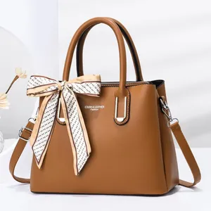 Close-up of brown stone pattern leather bag with decorative silk scarf and logo detail