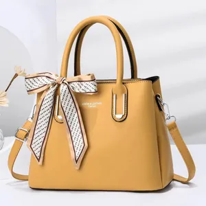Detail of yellow stone-pattern handbag with elegant silk scarf and CSGW logo