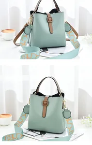 Detail of mint green bucket bag with leather strap, wide woven strap and gold hardware