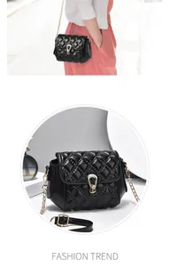 Detail view of black quilted crossbody bag with gold chain strap and U-shaped buckle
