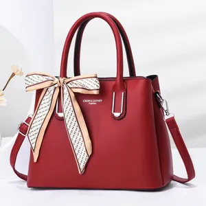 Detail of red stone texture handbag with brand logo and decorative silk scarf accessory
