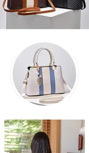 Detail of white monogram handbag with blue contrast stripe and leaf pendant