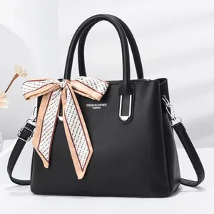 Close-up of black stone-pattern leather handbag featuring a decorative silk scarf and logo