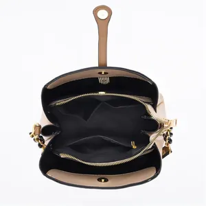 Interior view showing multiple compartments, zippers and gold chain of the beige bucket bag