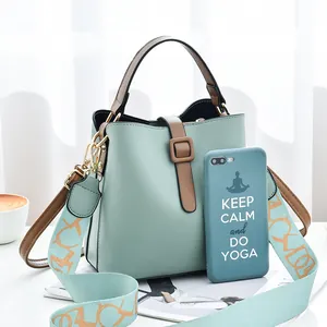 Chic mint green bucket bag with brown contrast handles and patterned wide strap