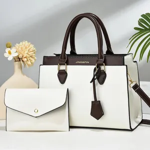 Detail of cream tote bag and matching clutch with dark brown handles in home setting