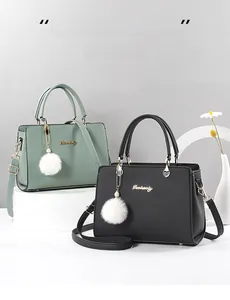 Close-up of black and green leather handbags with golden brand logo and plush charms