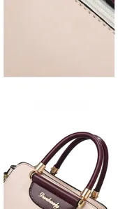 Detail of beige lychee grain leather handbag with burgundy handles and gold metal hardware