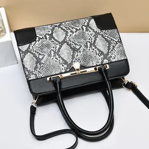 Large snakeskin patterned tote bag with black accents and golden hardware shown from above
