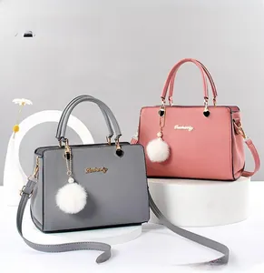 Detail of pink and grey leather handbags with plush heart charms on a display stand
