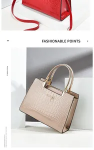 Detail of crocodile pattern patent leather handbag with metal logo and detachable strap