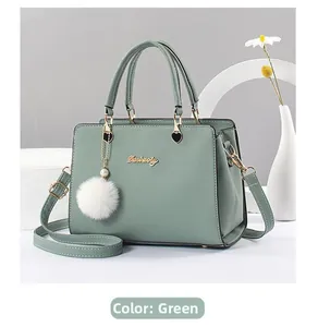 Detail of light green leather handbag with golden hardware and white fur charm