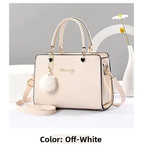 Detail of off-white handbag featuring golden lettering and soft white fur ball pendant