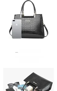 Detail view of black crocodile pattern handbag capacity with adjustable shoulder strap